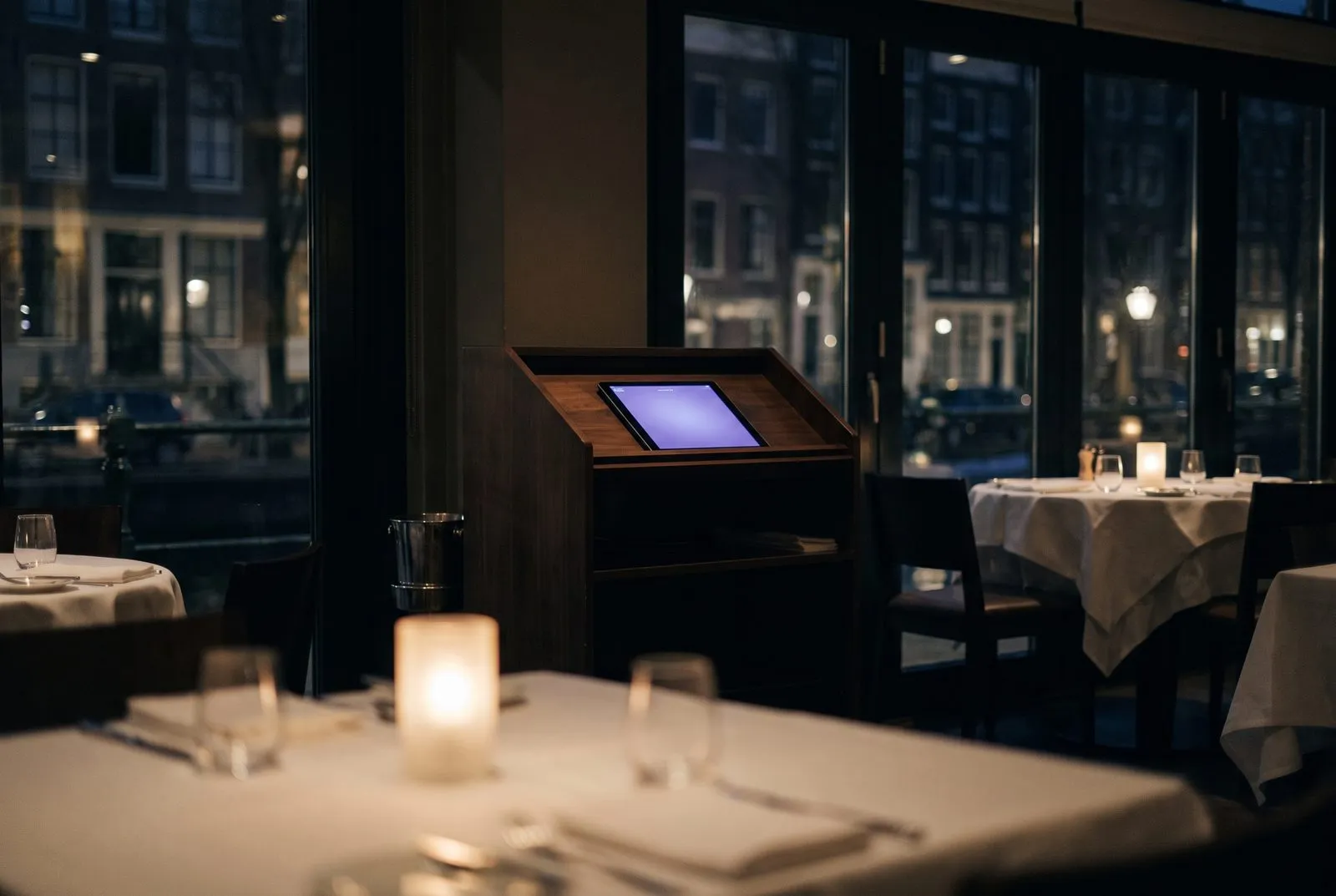 Nederlands restaurant in het blauwe uur met reserveringstablet op de gastheerstand — AI voor de horeca